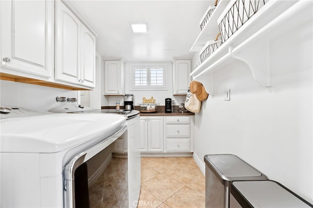 laundry area featuring light tile patterned floors, cabinets, and washing machine and clothes dryer