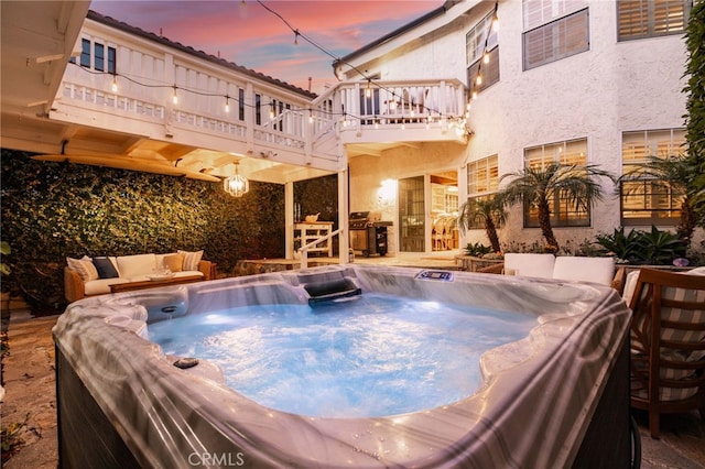 pool at dusk featuring an outdoor kitchen and a hot tub