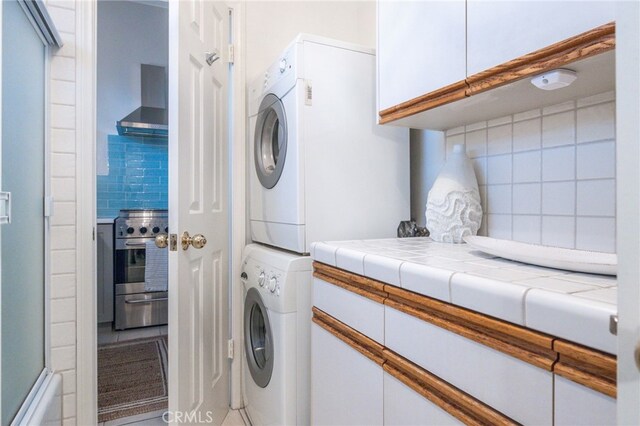 laundry room with cabinets and stacked washer / drying machine