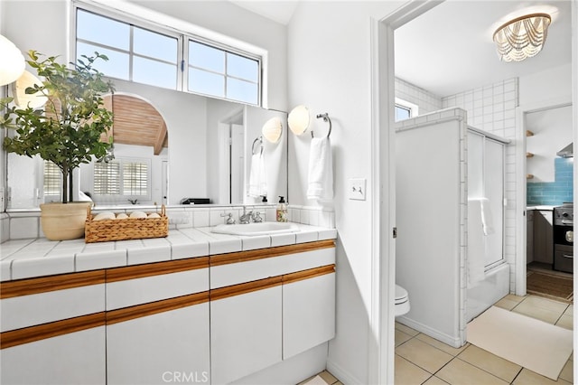 bathroom featuring vanity, toilet, an enclosed shower, and tile patterned flooring