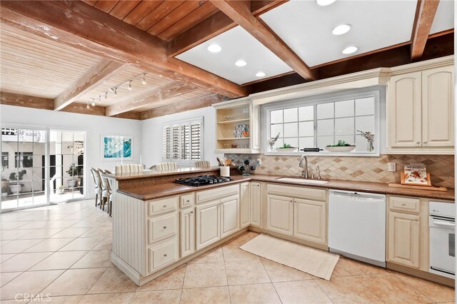 kitchen with beamed ceiling, sink, backsplash, and white appliances