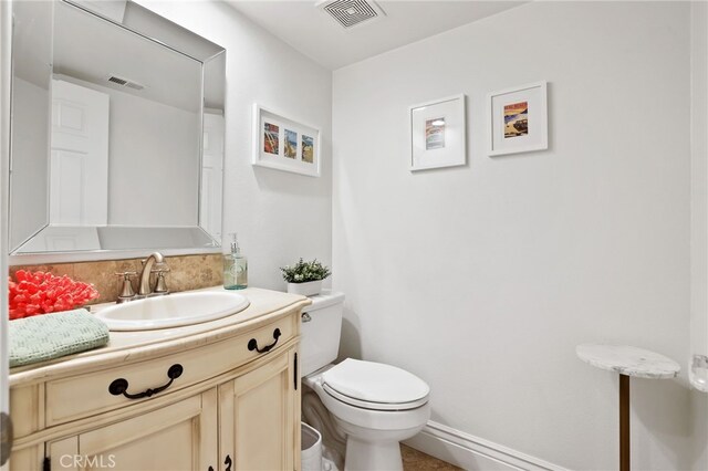 bathroom featuring vanity, toilet, and backsplash