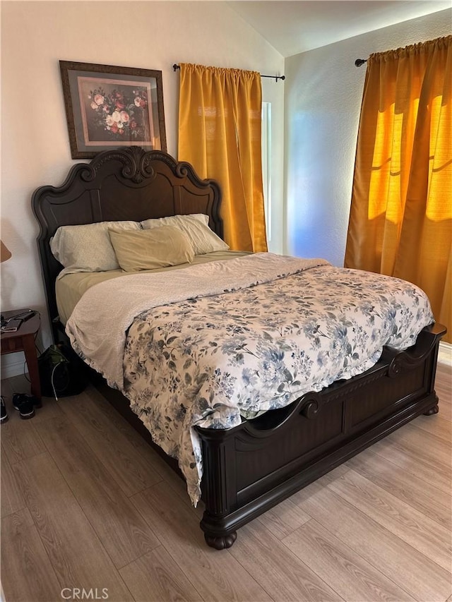 bedroom featuring wood-type flooring and vaulted ceiling