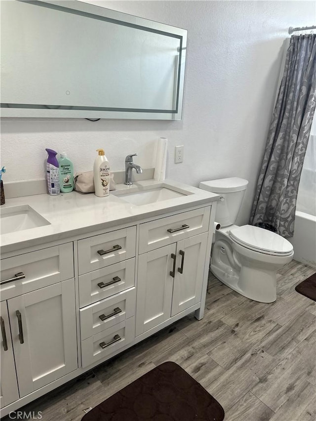 full bathroom featuring hardwood / wood-style flooring, vanity, shower / tub combo, and toilet