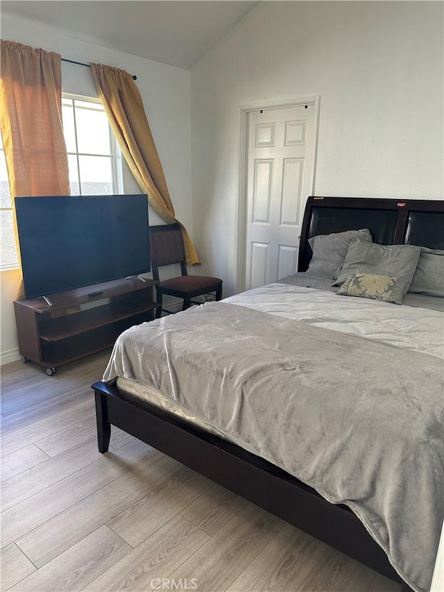 bedroom with vaulted ceiling and light hardwood / wood-style floors