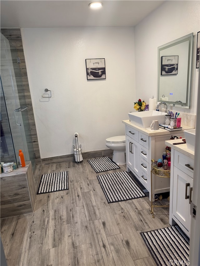 bathroom featuring vanity, wood-type flooring, a shower with door, and toilet