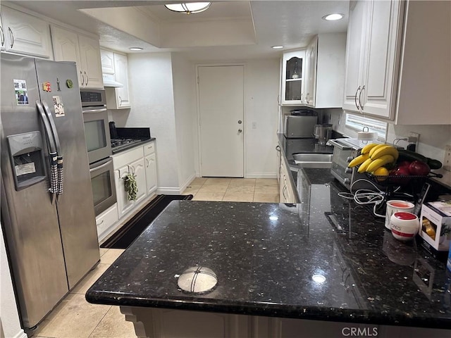 kitchen featuring a tray ceiling, kitchen peninsula, white cabinets, and appliances with stainless steel finishes