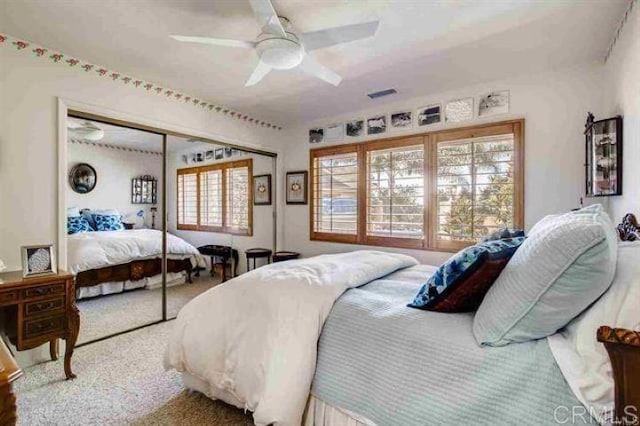 carpeted bedroom with ceiling fan and a closet