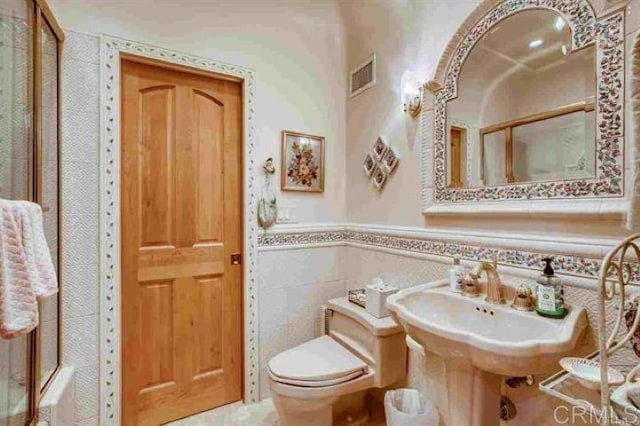 bathroom featuring an enclosed shower, tile walls, and toilet