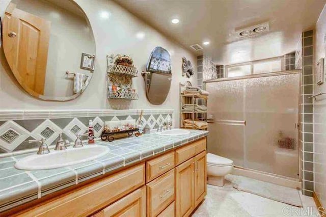 bathroom with tile patterned flooring, toilet, decorative backsplash, a shower with shower door, and vanity