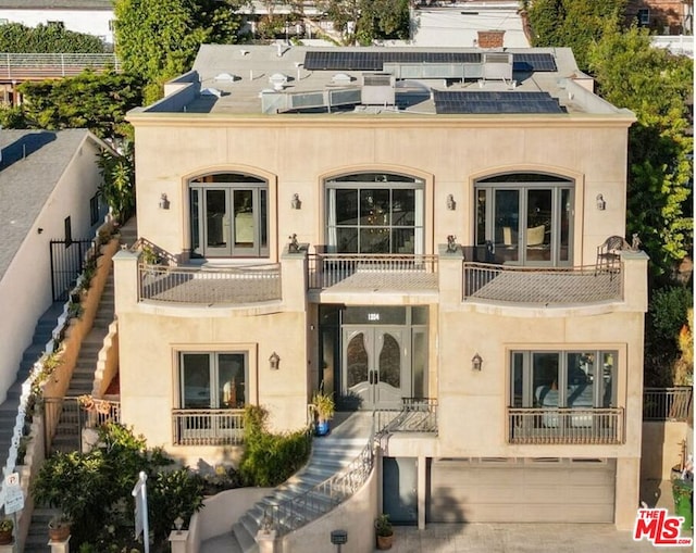 view of front facade featuring a garage, a balcony, and french doors