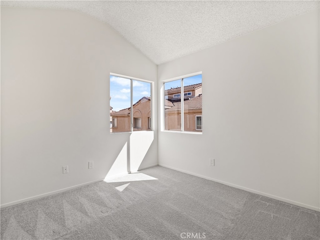 carpeted spare room with vaulted ceiling and a textured ceiling