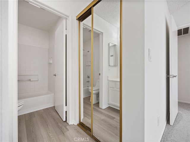 full bathroom with bathing tub / shower combination, hardwood / wood-style floors, vanity, and toilet