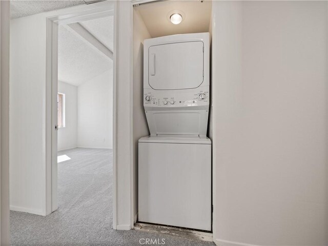 19810 Sandpiper Pl Unit 22, Newhall, CA 91321 - clothes washing area featuring baseboards, stacked washer and clothes dryer, a textured ceiling, and carpet flooring