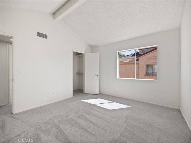 unfurnished bedroom featuring light colored carpet, a textured ceiling, and vaulted ceiling with beams