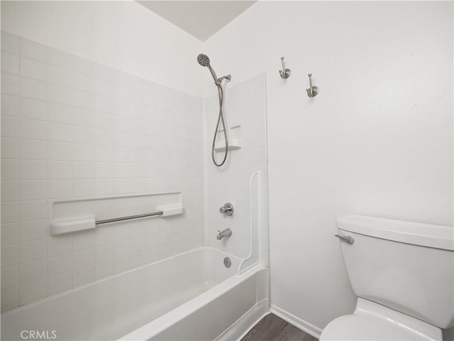 bathroom featuring tiled shower / bath combo, hardwood / wood-style flooring, and toilet