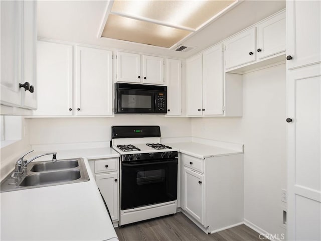 kitchen with sink, dark wood-type flooring, gas stove, and white cabinets