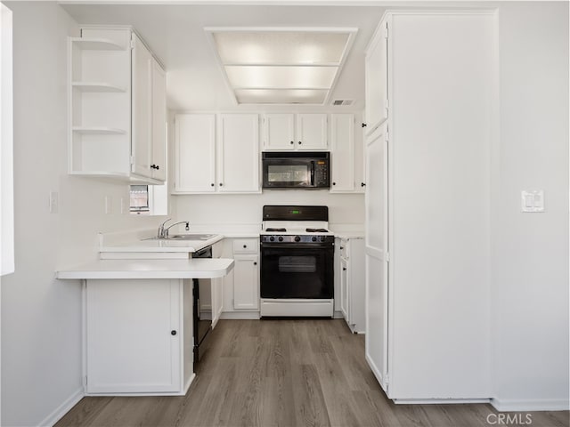 kitchen with sink, light hardwood / wood-style flooring, black appliances, and white cabinets