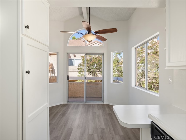 doorway to outside with vaulted ceiling with beams, a textured ceiling, light hardwood / wood-style floors, and ceiling fan