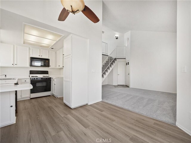 kitchen with sink, white cabinetry, light hardwood / wood-style flooring, ceiling fan, and white gas range oven