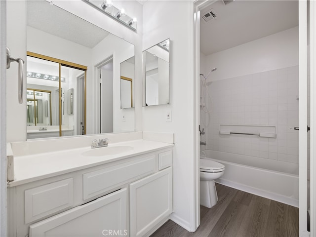 full bathroom with wood-type flooring, toilet, tiled shower / bath combo, and vanity