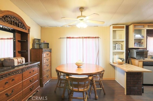 dining space with ceiling fan, dark wood-type flooring, and wood walls