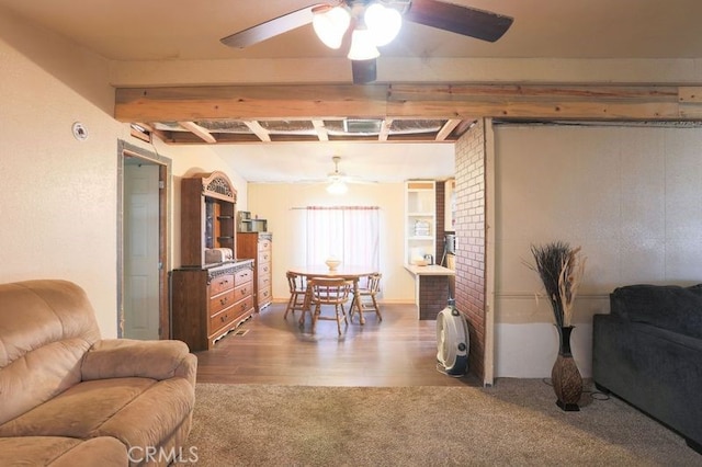 living room featuring ceiling fan, beamed ceiling, and wood-type flooring