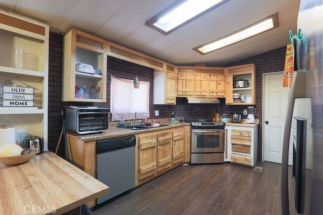 kitchen featuring sink, brick wall, dark hardwood / wood-style floors, vaulted ceiling, and appliances with stainless steel finishes