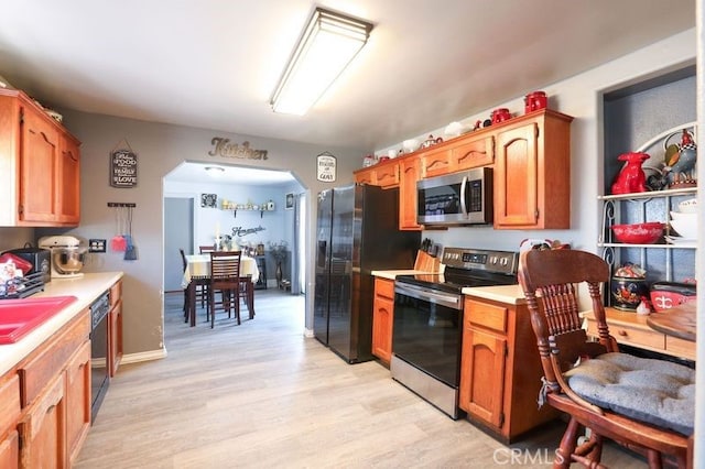 kitchen featuring black appliances, light wood-type flooring, and sink