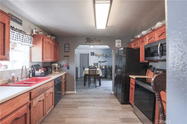 kitchen with appliances with stainless steel finishes, light wood-type flooring, and sink