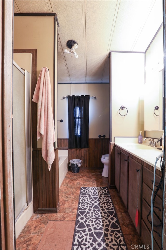 full bathroom featuring vanity, a textured ceiling, plus walk in shower, and wood walls