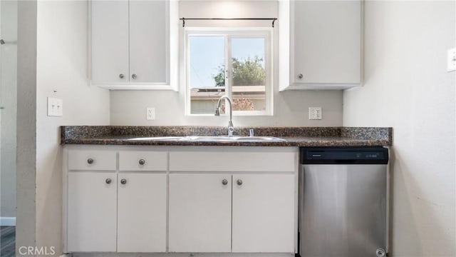 kitchen with white cabinetry, dark stone countertops, stainless steel dishwasher, and sink