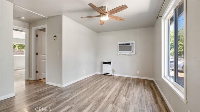 empty room featuring ceiling fan, light hardwood / wood-style floors, heating unit, and a wall mounted AC