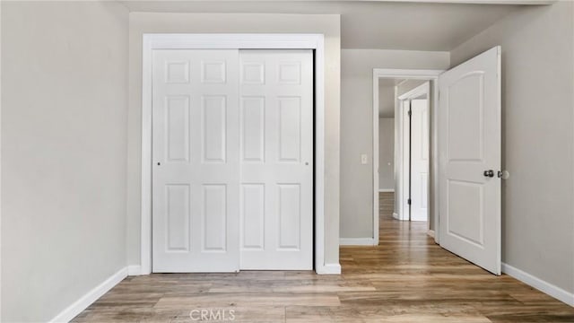 unfurnished bedroom with light wood-type flooring and a closet