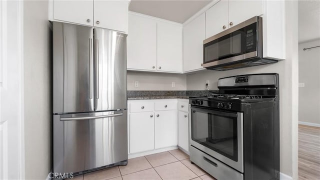 kitchen with light tile patterned flooring, appliances with stainless steel finishes, and white cabinetry