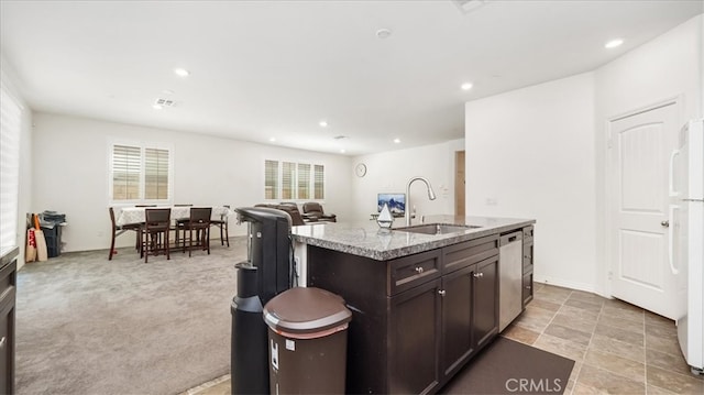 kitchen with dishwasher, dark brown cabinetry, a center island with sink, sink, and light colored carpet