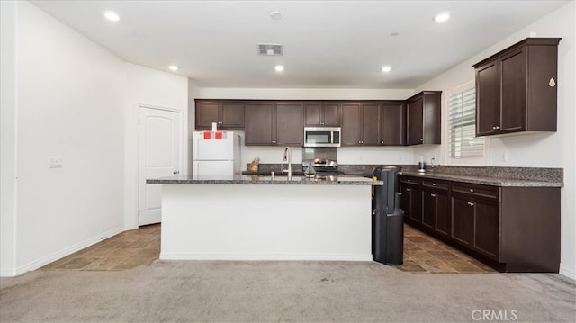 kitchen with carpet flooring, stainless steel appliances, a kitchen island with sink, and sink