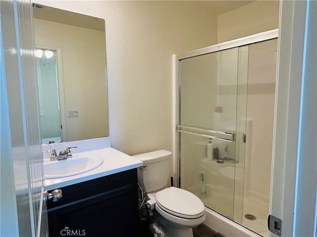 bathroom featuring vanity, toilet, and a shower with shower door