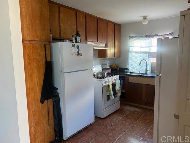 kitchen featuring dark tile patterned floors, sink, and white appliances