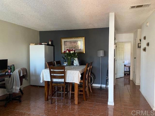 dining room featuring dark tile patterned flooring and a textured ceiling