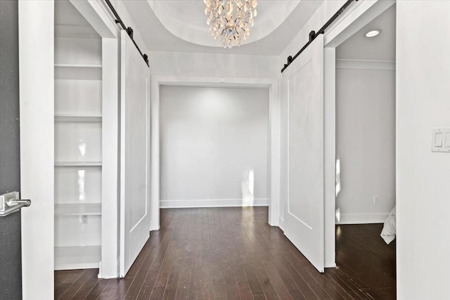 corridor featuring a barn door, hardwood / wood-style flooring, and a chandelier