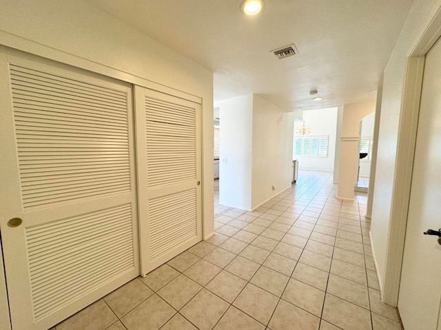 corridor with a chandelier and light tile patterned flooring