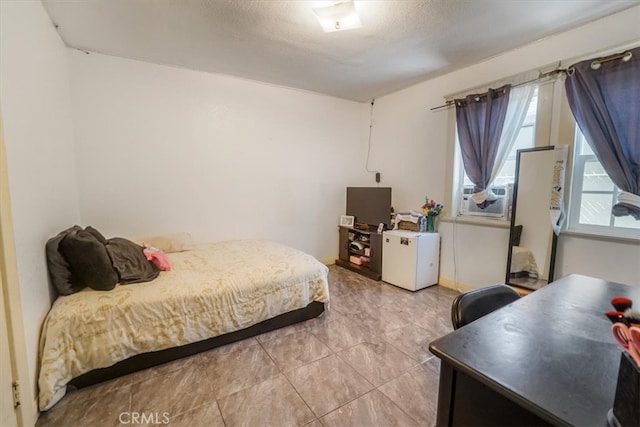 bedroom with cooling unit, refrigerator, and a textured ceiling