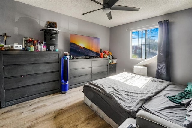 bedroom featuring light wood finished floors, a ceiling fan, and a textured ceiling