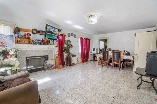 living area with a glass covered fireplace and light tile patterned floors