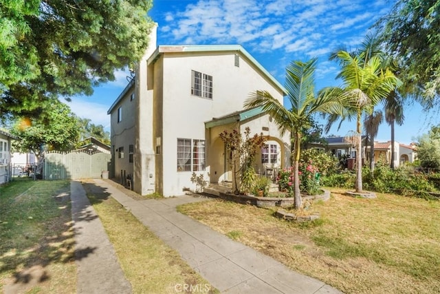 view of front of property featuring driveway, a front yard, fence, and stucco siding