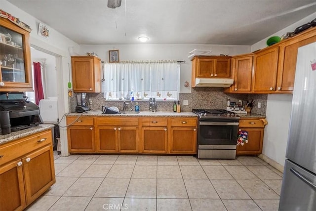 kitchen featuring under cabinet range hood, appliances with stainless steel finishes, and brown cabinets