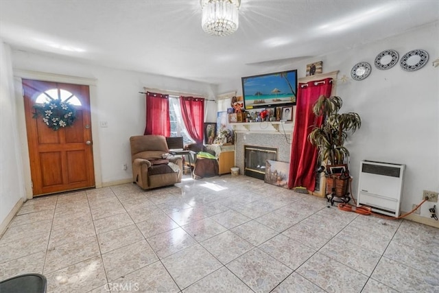 interior space with heating unit, baseboards, a chandelier, and a glass covered fireplace