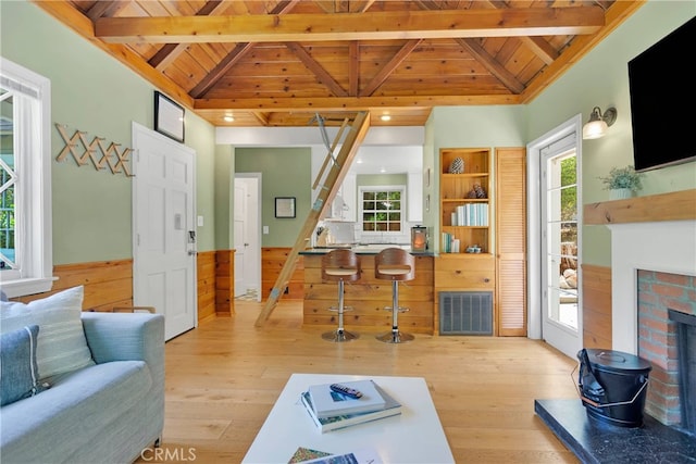 living room with lofted ceiling with beams, wooden walls, wooden ceiling, and light hardwood / wood-style floors