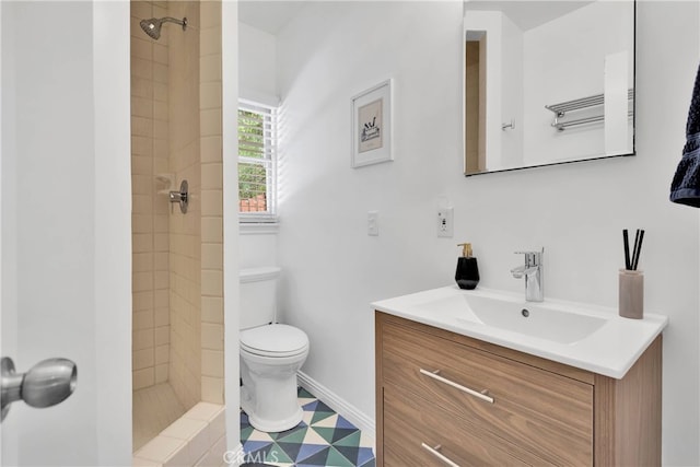 bathroom featuring a tile shower, vanity, and toilet